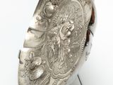 a silver plate that is on a stand on a white surface