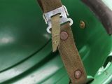 a close up of a green helmet with a strap on it