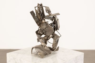sculpture en métal argenté représentant un homme tenant une guitare, posée sur un socle blanc