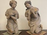 two statues sitting on top of a table with pictures on the wall