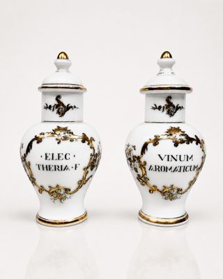 pair of white and gold vases with writing on them on a white surface
