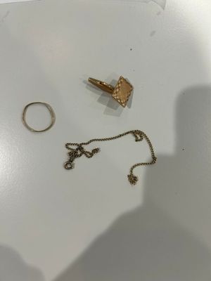 deux bagues et un collier en or posés sur une surface blanche