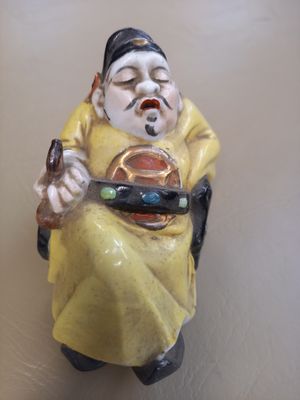 une figurine représentant un homme assis sur une chaise, tenant un téléphone portable