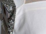 the back of a woman ' s white dress with silver sequins on it