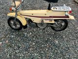 un petit scooter jaune garé sur le gravier