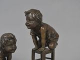 two statues of children sitting on stools next to each other