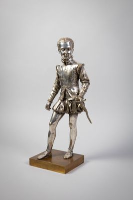 a silver statue of a man with a sword on a wooden base