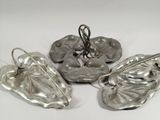 three pieces of silver metal are sitting on a white surface