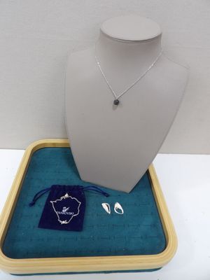 un ensemble composé d'un collier et de boucles d'oreilles, posé dans un plateau sur une table