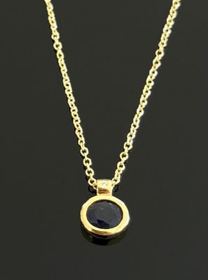 un collier en or avec une pierre noire suspendue à une chaîne