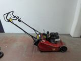a red lawn mower sitting on the floor in a room
