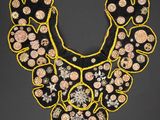 a black and yellow embroidered necklace with flowers on it