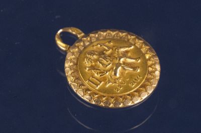 un pendentif en or sur lequel est représenté un homme et une femme