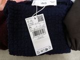 three pairs of sweaters with price tags on them sitting on a couch