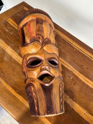 un masque en bois posé sur une table en bois