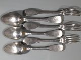 six cuillères en argent et une fourchette posées sur un plateau blanc