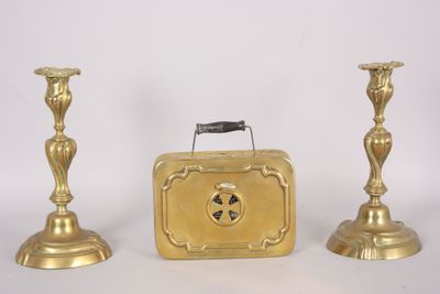 two gold candlesticks and a suitcase on a white surface