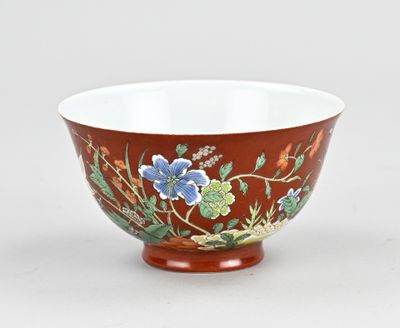un bol orange orné de fleurs bleues, posé sur une surface blanche