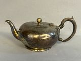 a silver teapot on a table with a white background