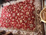 a red rug on the floor next to a wicker chair