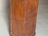 une petite armoire en bois avec un dessus noir, posée sur un sol carrelé