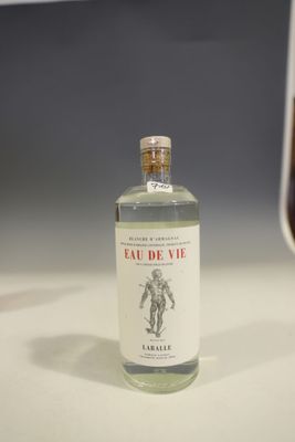 a bottle of alcohol sitting on a table next to a glass of wine