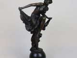 bronze statue of a woman holding a bird on a pedestal