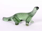 une figurine en verre vert représentant un dinosaure posée sur une surface blanche
