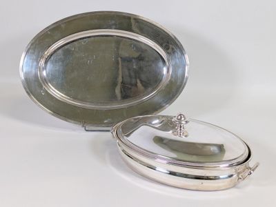 un plateau en argent muni d'un couvercle en verre, posé sur une table blanche