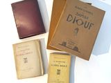 Plusieurs vieux livres sont posés les uns à côté des autres sur une surface blanche.