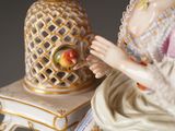 a figurine of a woman sitting on a table next to a pineapple