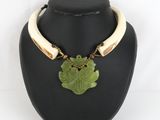 a necklace with a green leaf pendant on a black mannequin