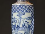 a blue and white vase sitting on a table with a lamp on it