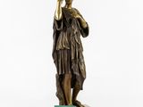 an antique bronze statue of a woman holding a glass