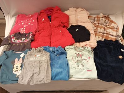 une boîte remplie de vêtements pour bébé posée par terre