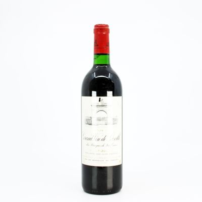 the bottle of red wine is sitting on a white surface