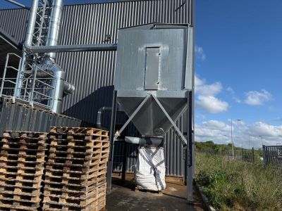 des piles de palettes empilées à l'extérieur d'un bâtiment, à côté d'une haute tour