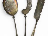 two silver spoons and a knife on a white surface