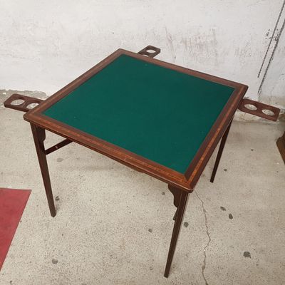 une petite table au plateau vert posée sur un sol en béton