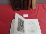 Plusieurs vieux livres sont posés sur une table rouge recouverte d'une nappe rouge.