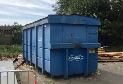 une benne bleue posée au milieu d'un terrain