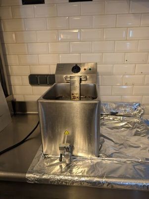 un évier en métal dans une cuisine où il y a beaucoup de papier d'aluminium sur le plan de travail