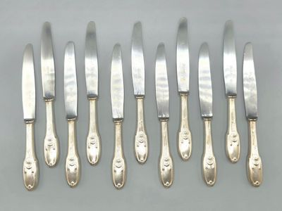 six silverplated knives and six knives on a table