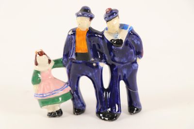 three figurines of a man and a woman standing next to each other