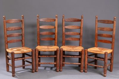 quatre chaises en bois sont alignées contre un mur gris