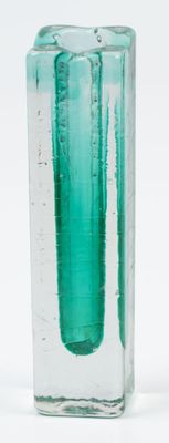 a green glass vase with water in it on a white surface