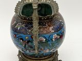 a vase with a peacock on top of it on a stand