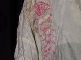 a close up of a white dress with pink flowers on it