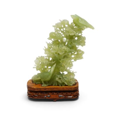 jade sculpture of flowers and leaves on a wooden base on a white background
