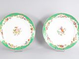 two green and white plates with flowers on them sitting on a table